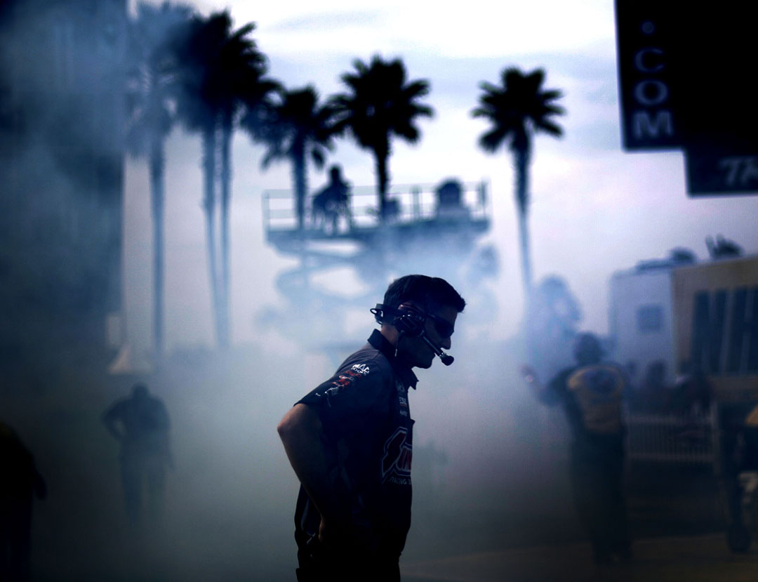 A crew members stands in the smoke after a burnout during the semifinals of the 2015 NHRA Gatornationals at Auto-Plus Raceway on Sunday, March 15, 2015 in Gainesville, Fla. (Matt Stamey/Staff photographer)