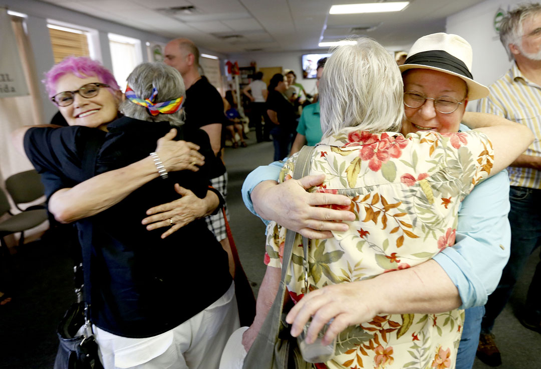 Lorelei Esser, left, hugs Corky Culver while Sus Austill, right, hugs a friend during a celebration at the Pride Community Center on Friday, June 26, 2015 in Gainesville, Fla. The center hosted the gathering to celebrate the Supreme Court's ruling that all 50 states must allow same-sex marriage. (Matt Stamey/Staff photographer)