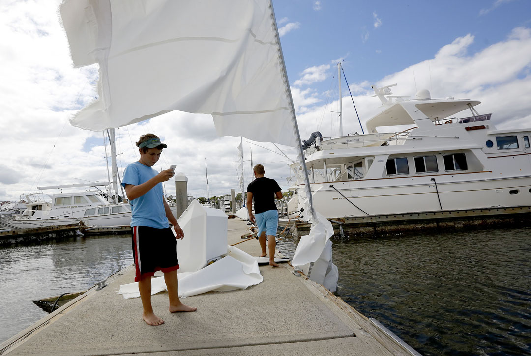 While standing under a sail, Walker Daivs takes a video of the sunken boat at the Conch Marina after Hurricane Matthew on Friday, Oct. 8, 2016 in St. Augustine, FL. Davis details boats for many of the owners and came to the maria to check on the vessels. Matt Stamey/Gainesville Sun