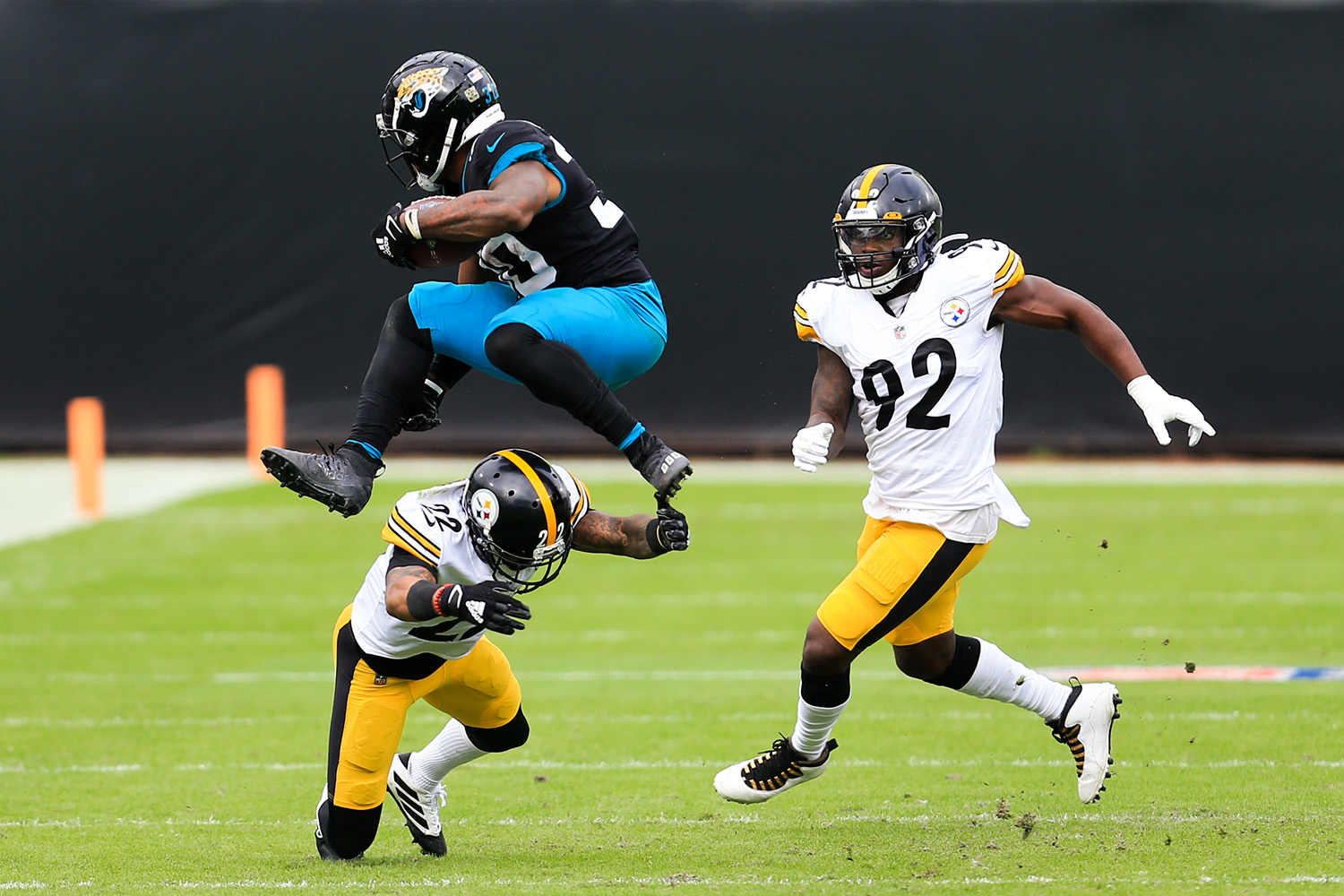 Jacksonville Jaguars running back James Robinson, left, leaps over Pittsburgh Steelers cornerback Steven Nelson (22) as linebacker Olasunkanmi Adeniyi (92) comes in to help during the first half of an NFL football game, Sunday, Nov. 22, 2020, in Jacksonville, Fla. (AP Photo/Matt Stamey)