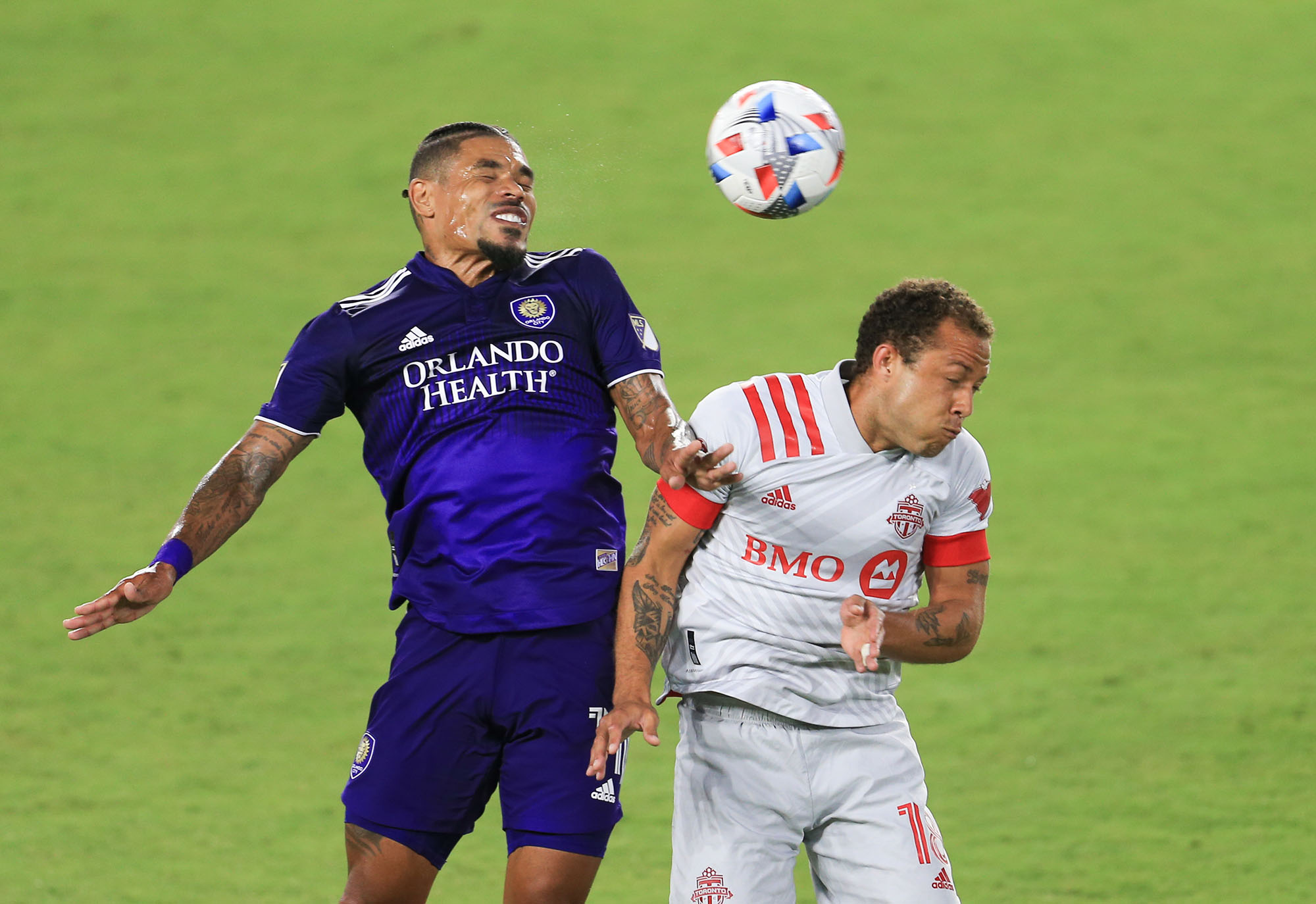 May 22, 2021; Orlando, Florida, USA; Orlando City midfielder Junior Urso (11) and Toronto FC midfielder Nick DeLeon (18) jump for the ball at Orlando City Stadium. Mandatory Credit: Matt Stamey-USA TODAY Sports